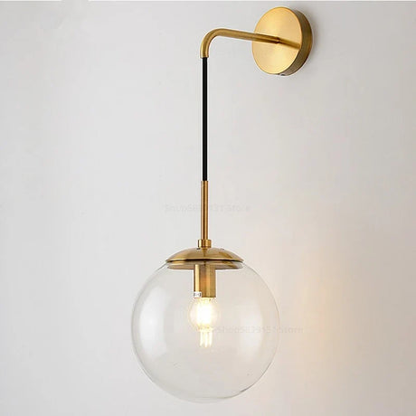 Elegant gold wall light with a clear globe shade and stylish arm for a modern decor