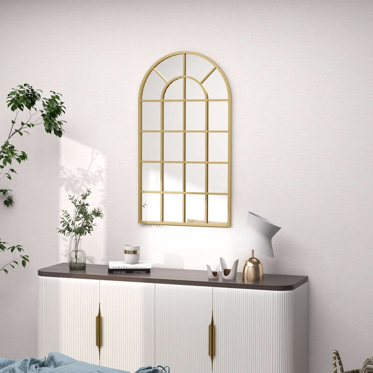 Stylish gold-framed wall mirror in an arch design above a modern sideboard for elegant bathroom decor