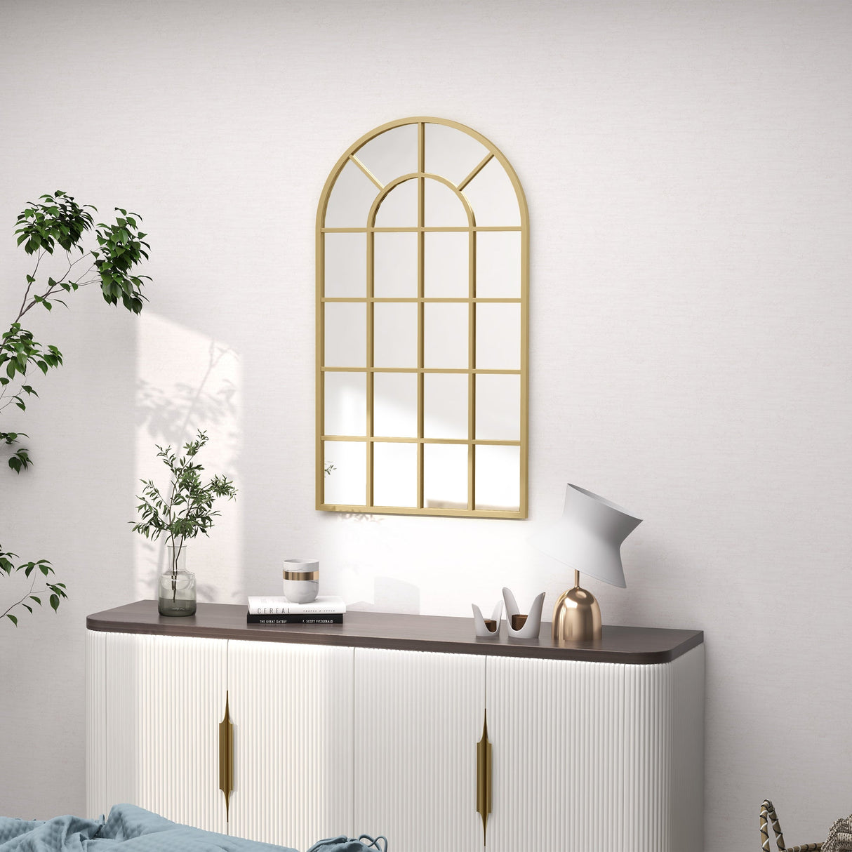 Stylish gold-framed wall mirror in an arch design above a modern sideboard for elegant bathroom decor