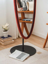 Elegant Nisu Home Wall Mirror with a sleek velvet frame, standing on a black base in a stylish interior