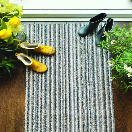 Striped washable mat placed near a door with flower pots and shoes on it