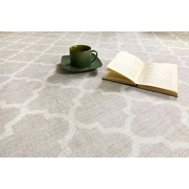 Light pink patterned washable rug with a cup and an open book on it