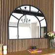 Jobu Home Window Mirror with an arch design, framed in black against a wooden backdrop