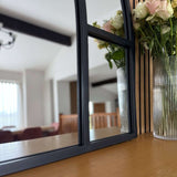 Jobu Home Window Mirror with a Black Frame Reflecting a Floral Arrangement on a Wooden Table