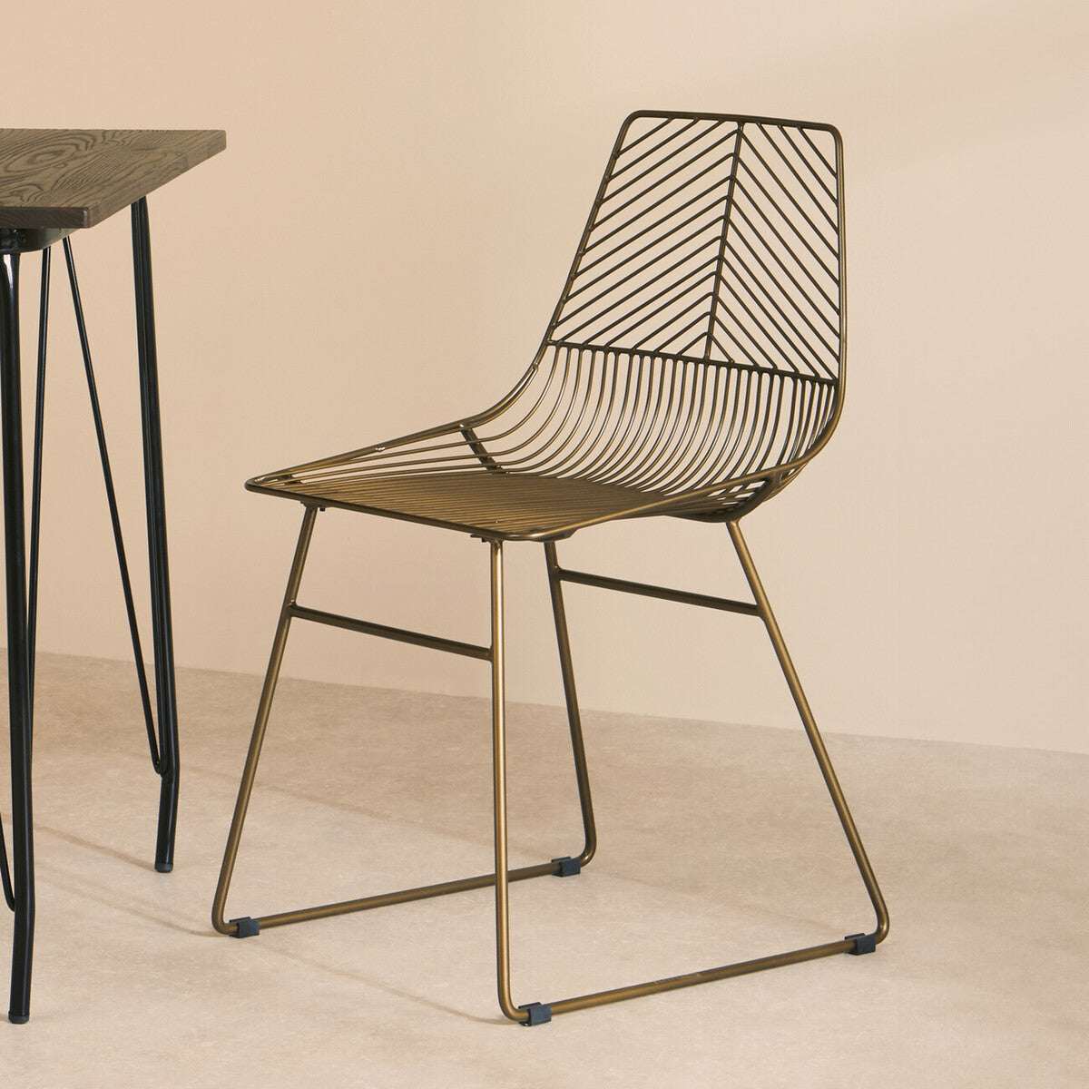 Orsina Wire Chair in bronze with geometric design paired with a minimalist black table