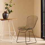 Orsina Wire Chair in a minimalist setting beside a wooden table with decorative vase