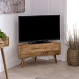 Verty Furniture Corner TV Stand in natural wood finish with a TV and decorative plants in a modern living room