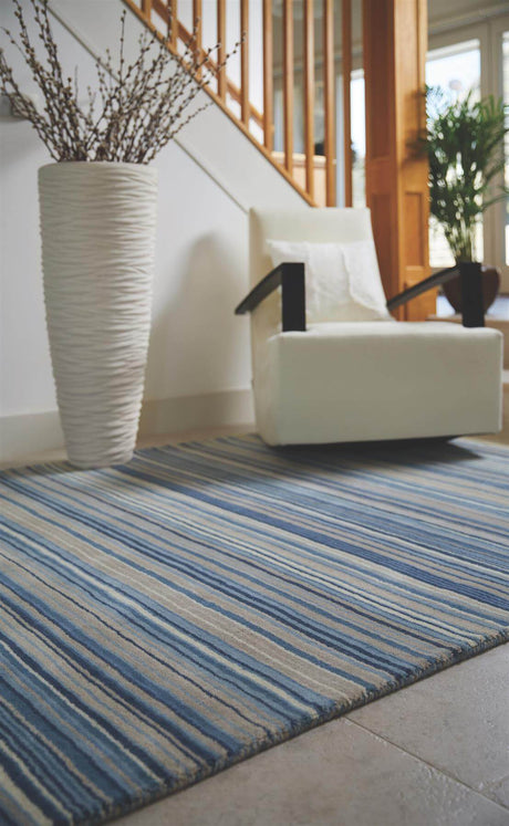 Striped blue and beige wool rug placed under a chair and vase for a stylish interior