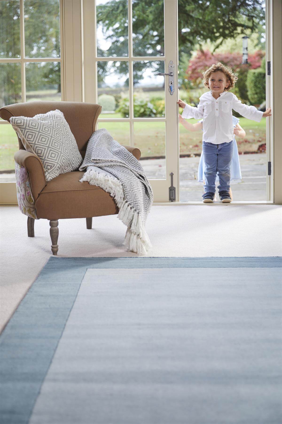 Light blue wool rug in a spacious living area with a child standing by the door