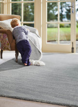 Child playing on a soft grey Wool Rug in a bright living room with large windows