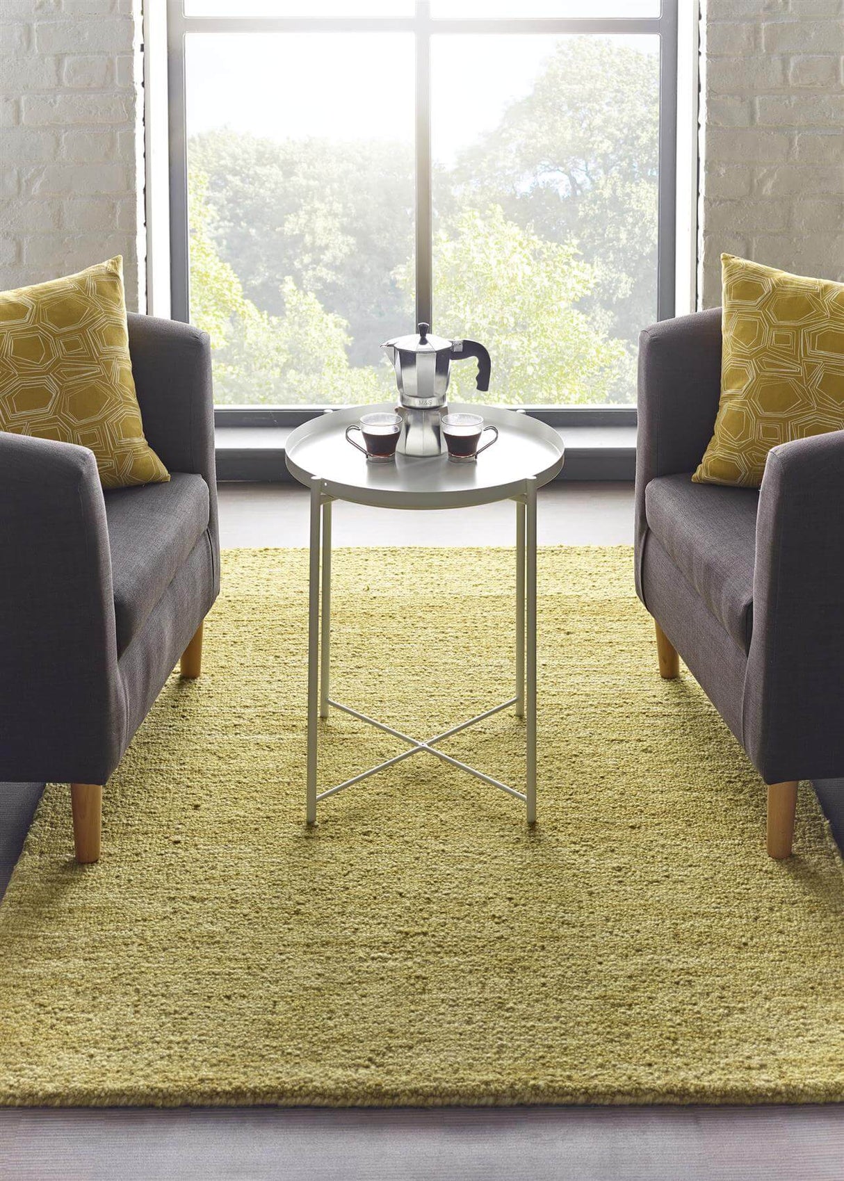 Cozy yellow wool rug placed between two grey armchairs in a bright living room