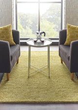 Cozy yellow wool rug placed between two grey armchairs in a bright living room