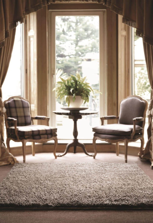Soft textured Wool Rug placed in a cosy living room with two chairs and a potted plant